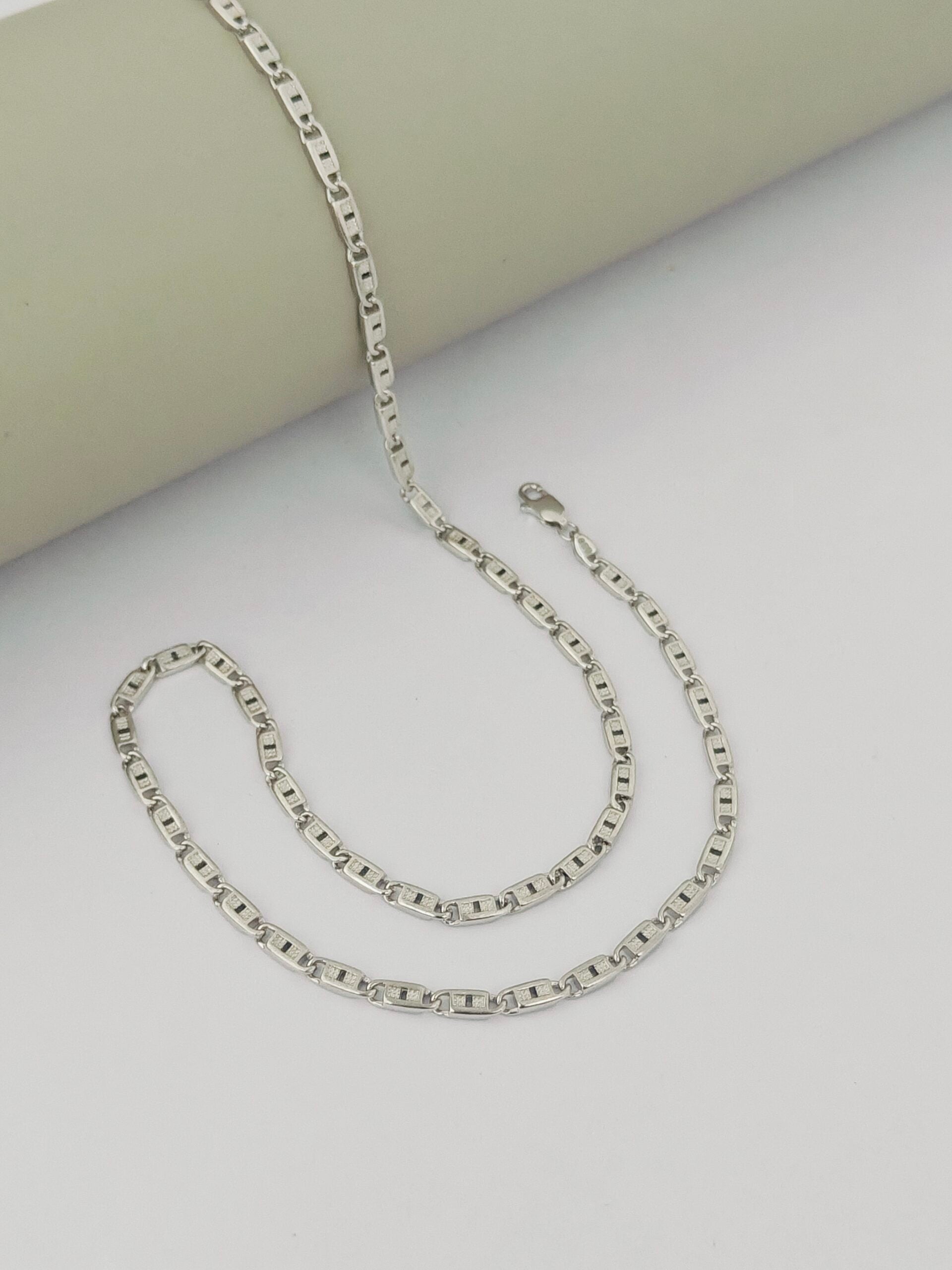 Silver chain necklace on a light gray surface